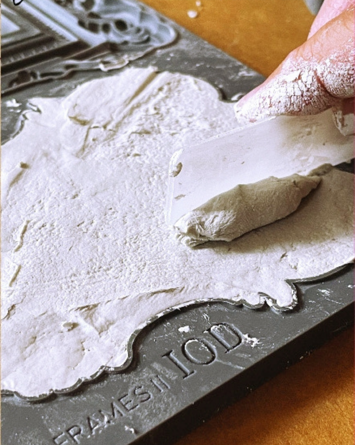 Hand applying white plaster with flat tool to I.O.D. Frames 2 Mould by Iron Orchid Designs.