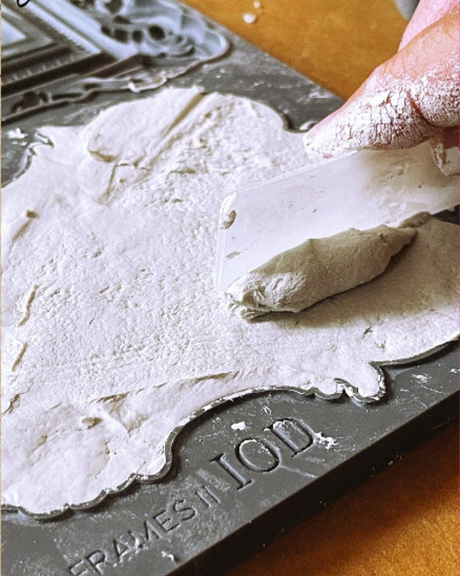 Hand applying white plaster with flat tool to I.O.D. Frames 2 Mould by Iron Orchid Designs.