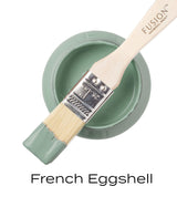 Open jar of Fusion Mineral Paint in French Eggshell with brush dipped in paint resting on the rim.