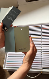 Hands hold Fusion Briefcase Swatch Box Set by Fusion Mineral Paint above an array of other color samples.