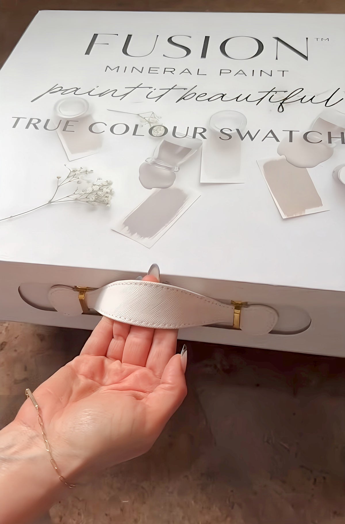 Hand pulling white ribbon handle on Fusion Mineral Paint Briefcase Swatch Box Set.