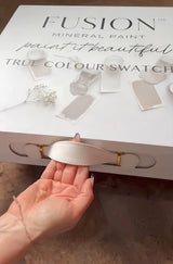Hand pulling white ribbon handle on Fusion Mineral Paint Briefcase Swatch Box Set.