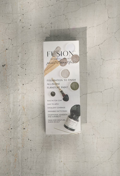 Fusion Mineral Paint box with True to Color Card (2024) and paint chips displayed on cracked concrete.