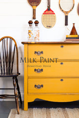 Yellow dresser painted in Homestead House Garden Seed Milk Paint, styled with vintage rackets.