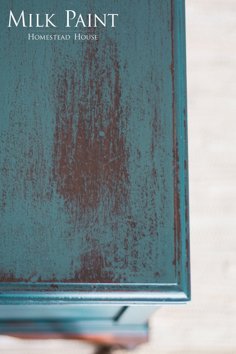 Teal wood surface painted in Gaspe Green Milk Paint by Homestead House, brand name at top left.