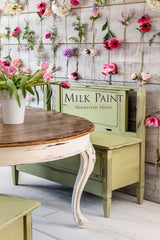 Homestead House Gatineau Milk Paint bench beside a wooden table, flowers displayed on a wood wall in background.