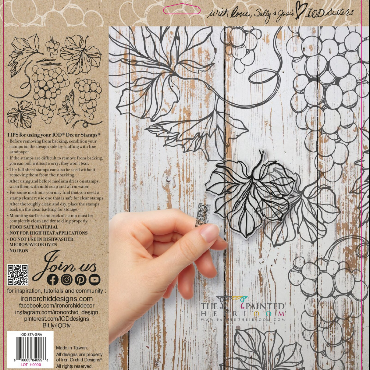 Hand holds Grapes Stamp (Retired) by IOD featuring grape and leaf designs on a whitewashed wood background.