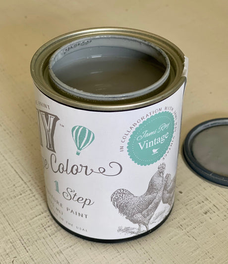 Open can of Gray Skies DIY Cottage Color by DIY Paint Co. with vintage lid placed beside it.