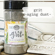 Grit Aging Dust by Sweet Pickins from Old Fashioned Milk Paint next to carved wood on a floral cloth.