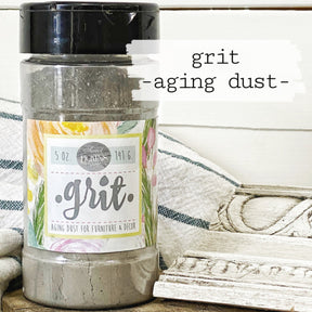 Grit Aging Dust by Sweet Pickins from Old Fashioned Milk Paint next to carved wood on a floral cloth.