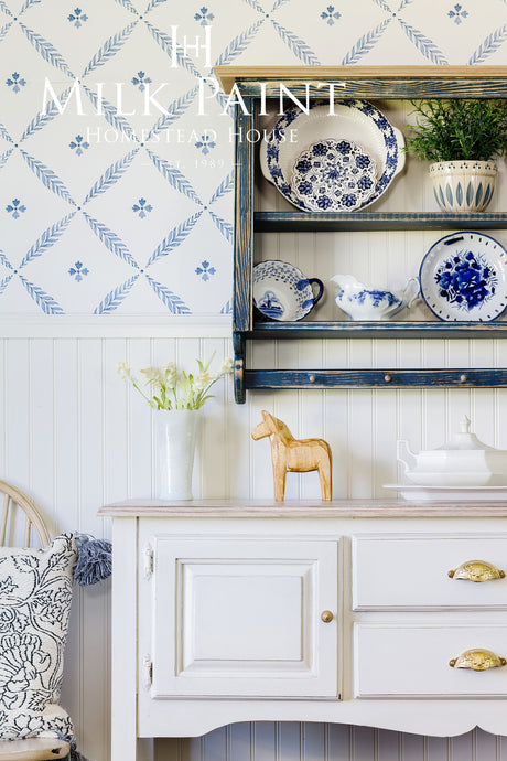 Gustavian White Milk Paint sideboard by Homestead House with blue dishes, wooden horse, and teapot on top.
