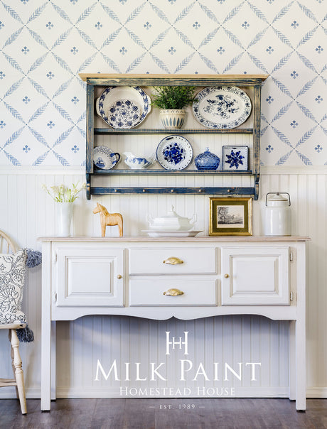 Homestead House sideboard in Gustavian White Milk Paint with gold handles and blue plates on top.