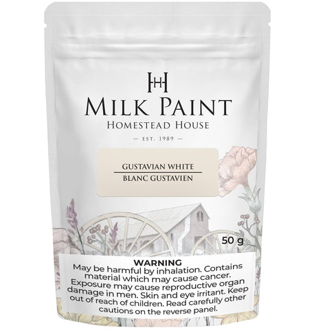 Homestead House Gustavian White Milk Paint 50g bag featuring floral-wagon artwork and a safety label.