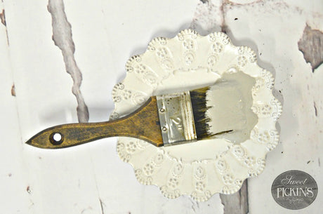 Wooden-handled brush with bristles dipped in Haberdash by Sweet Pickins Milk Paint rests on a plate.