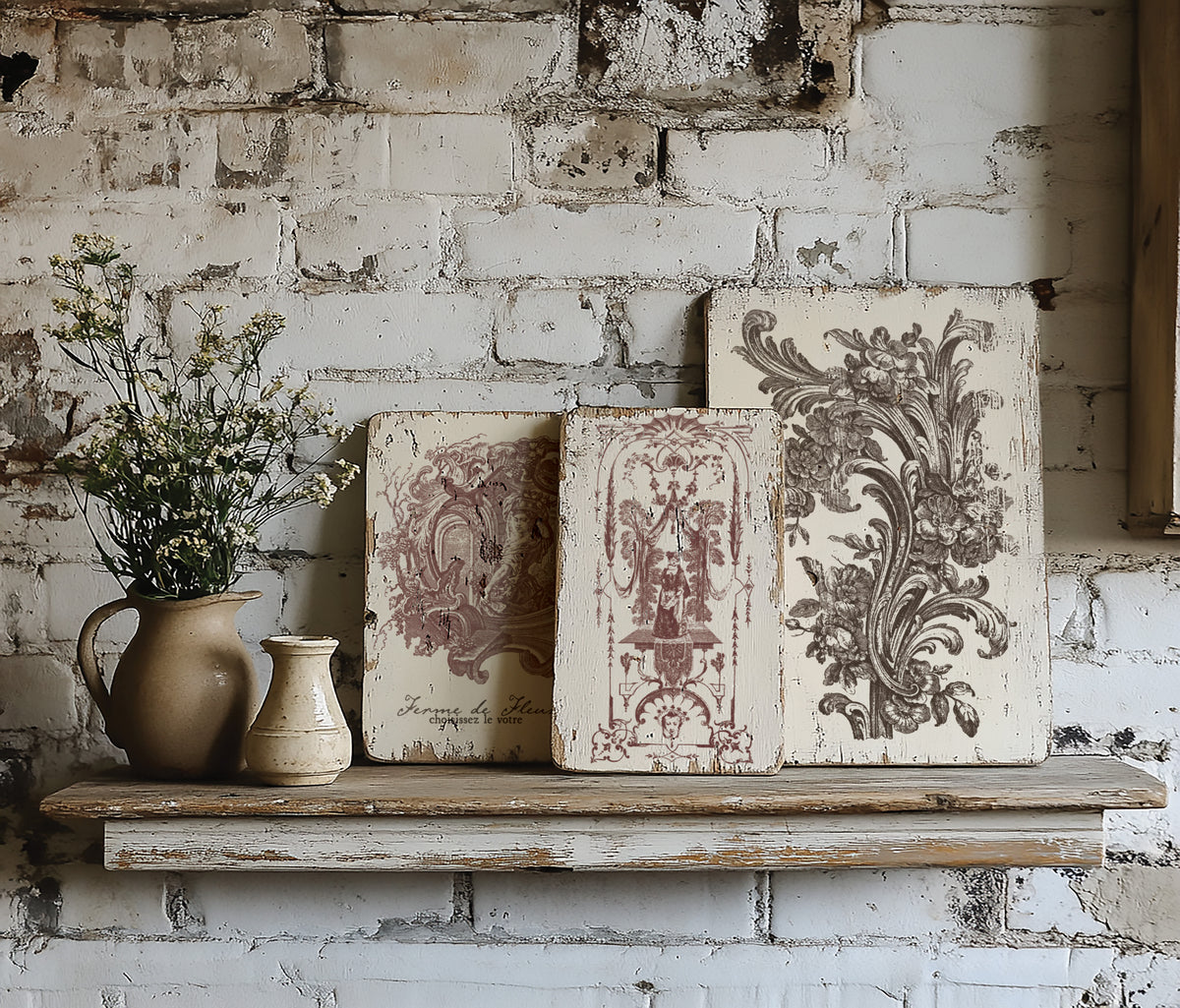 Three I.O.D. Hameau de la Reine Paint Inlay boards displayed on a white brick shelf.