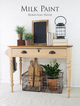 Beige wooden table with decor accents, finished with Homestead House Hampton Milk Paint.