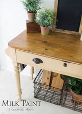 Wooden table with drawer, potted plants, and crates; Hampton Milk Paint by Homestead House text at bottom.