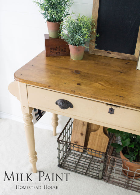 Wooden table with drawer, potted plants, and crates; Hampton Milk Paint by Homestead House text at bottom.