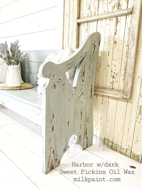 Distressed bench in Harbor by Old Fashioned Milk Paint, weathered door behind, vase on plate, text in corner.