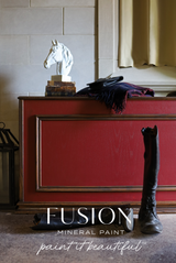 Red cabinet painted in Fusion Mineral Paint’s Highlander, with a horse head statue, folded clothes, and boots in front.