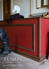 Scarlet red wooden bench painted with Fusion Mineral Paint Highlander, shown with riding boots, helmet, and sculpture.