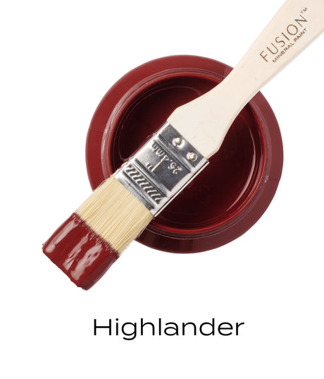 Paintbrush with scarlet paint resting on open jar of Highlander by Fusion Mineral Paint.