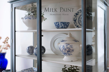 China cabinet in Homestead Blue Milk Paint with blue and white porcelain displayed on glass shelves.