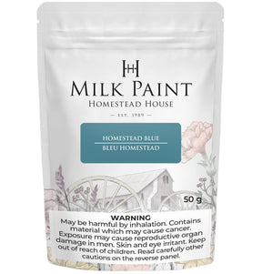 Homestead Blue Milk Paint by Homestead House, 50g pouch with floral wagon art and warning label on package.