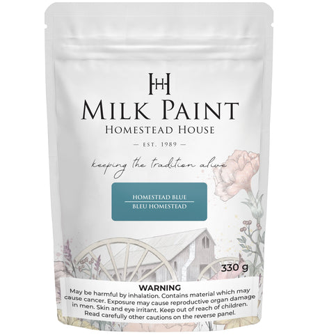 330g Homestead House Homestead Blue Milk Paint bag with floral and wagon wheel label illustrations.