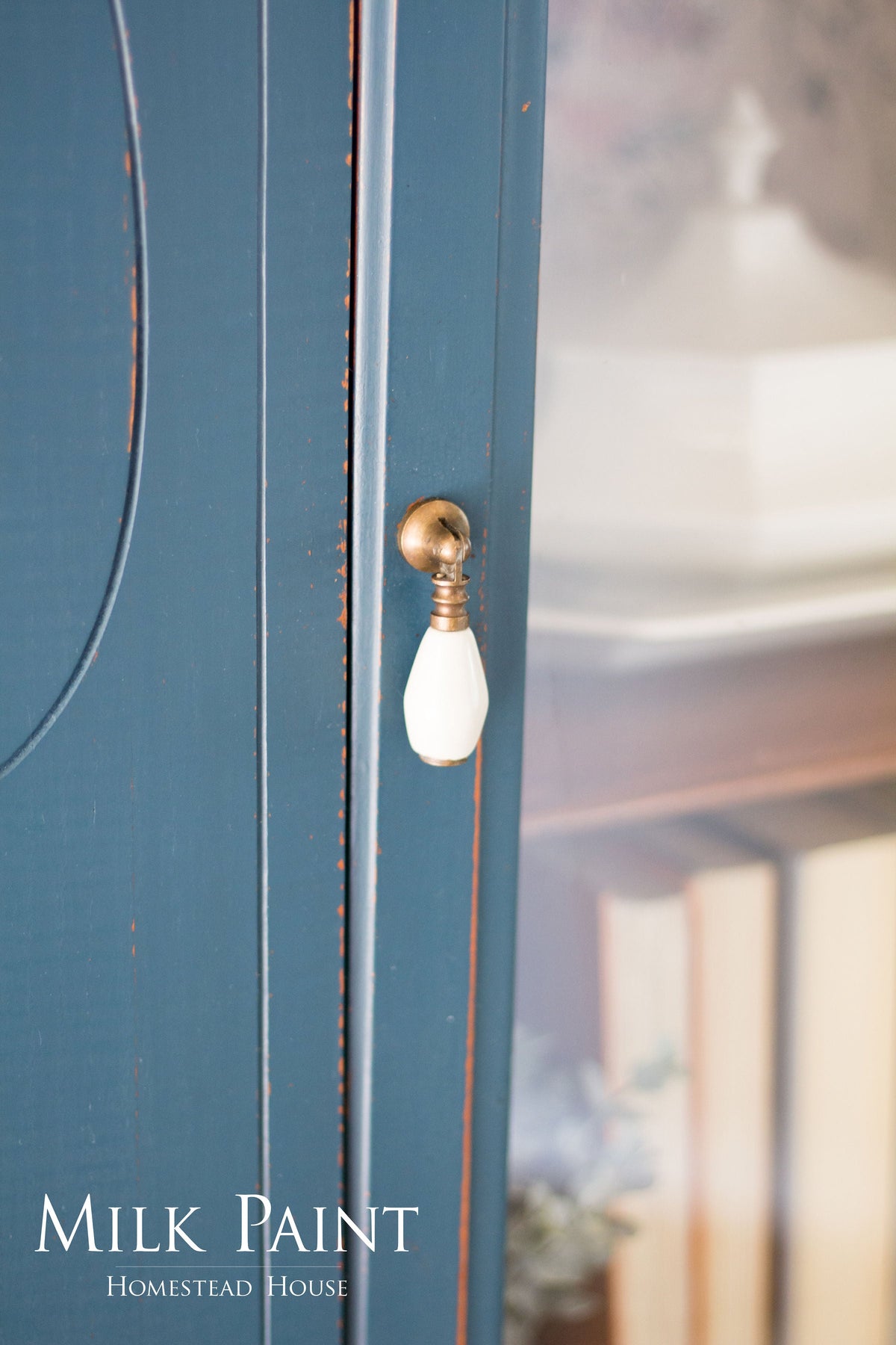 Homestead House cabinet in Homestead Blue Milk Paint with brass hardware, books and decor inside.