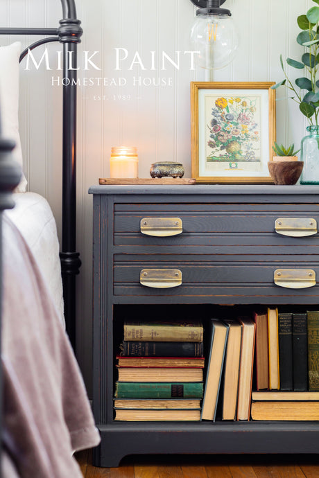 Dark wood nightstand in Homestead Grey Milk Paint, topped with books and art.