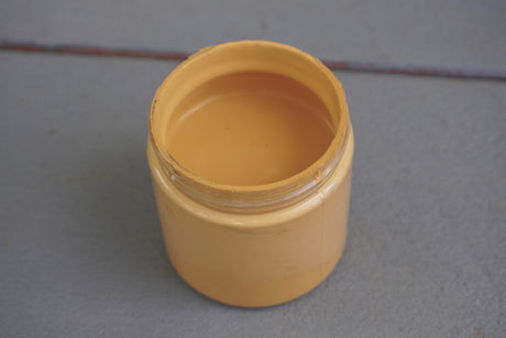 Open jar of Honey DIY Cottage Color by DIY Paint Co. with yellow paint visible inside.