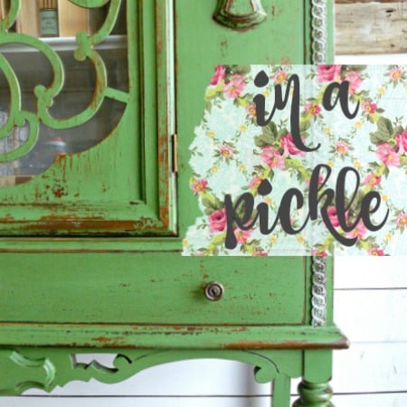 Green vintage cabinet painted in In A Pickle by Old Fashioned Milk Paint beside a floral “in a pickle” sign.