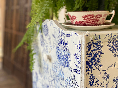 Dresser with I.O.D. Indigo Floral Paint Inlay, topped with a teacup and green fern leaves nearby.