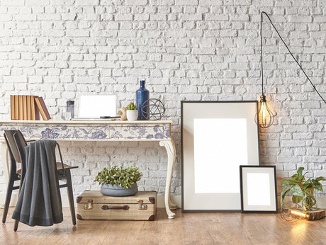 Indigo Floral Paint Inlay by I.O.D. displayed on desk with books, plant, and decor against white brick wall.