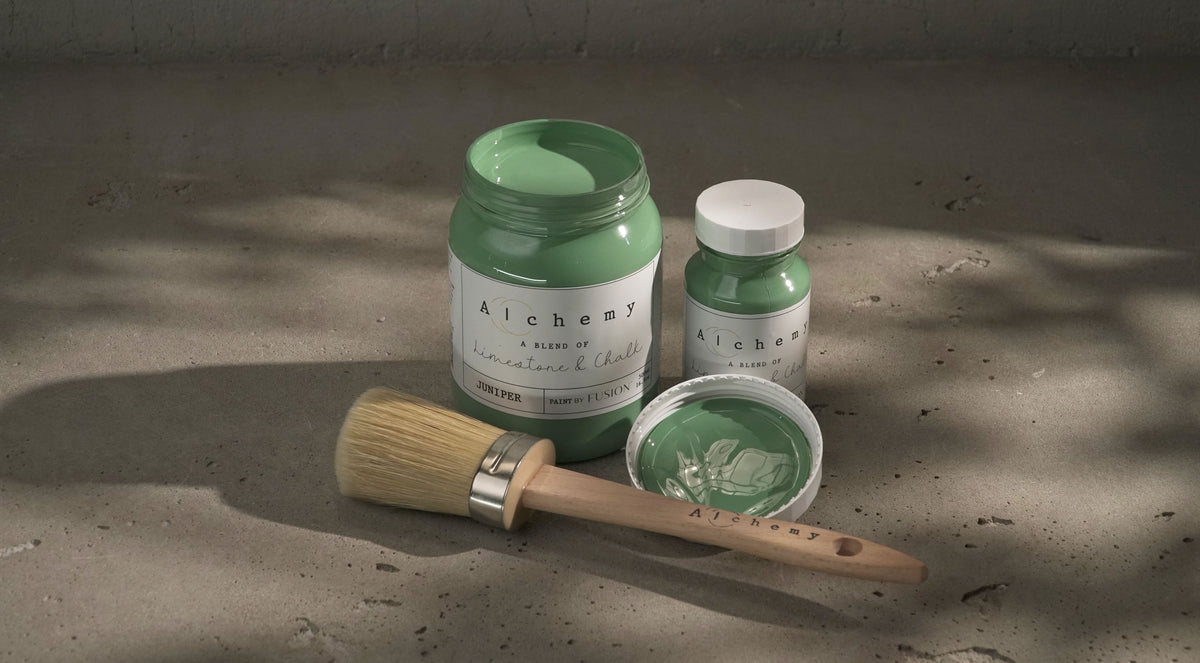 Two jars of Juniper Alchemy Paint by Fusion Mineral Paint, one open with a brush resting across the top.