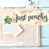 Just Peachy“ sign with floral accents, painted in Old Fashioned Milk Paint, plus paper flower and book.