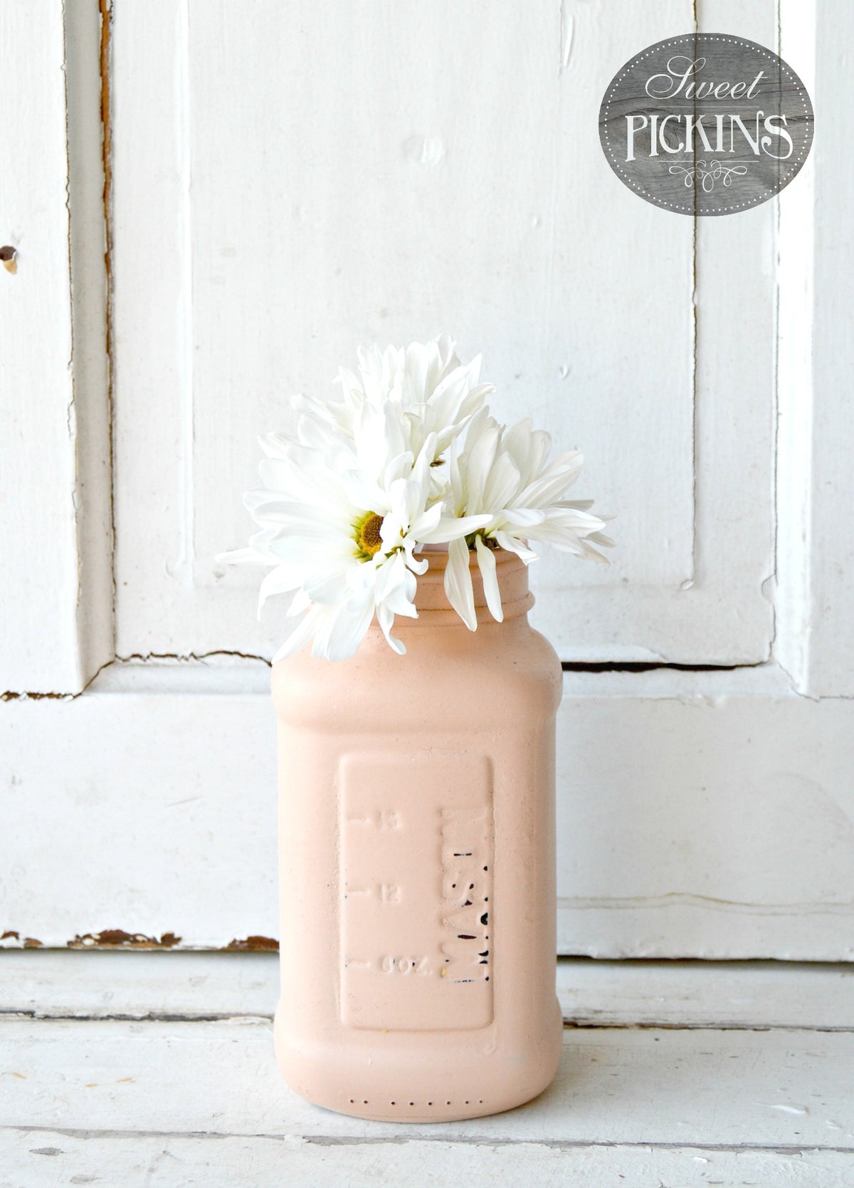 White daisies in a Just Peachy by Old Fashioned Milk Paint jar.