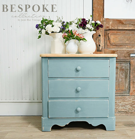 Small blue dresser painted Kent by Old Fashioned Milk Paint with 3 drawers; white vases on top.