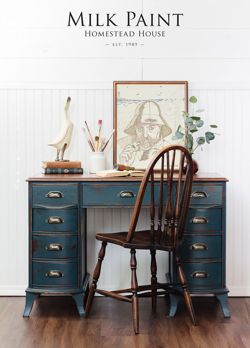 Vintage blue desk painted with Kentucky Green Milk Paint by Homestead House, with art supplies, books, and wooden chair.