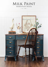 Vintage blue desk painted with Kentucky Green Milk Paint by Homestead House, with art supplies, books, and wooden chair.