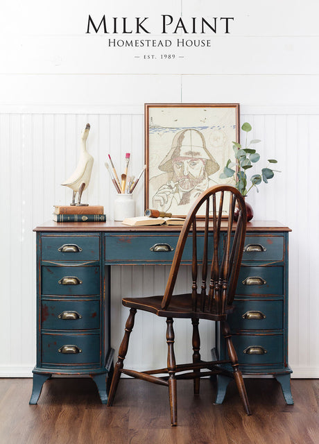 Vintage blue desk painted with Kentucky Green Milk Paint by Homestead House, with art supplies, books, and wooden chair.