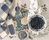 Homestead House Kurbits Indigo Milk Paint with paint supplies and a bowl of blueberries on floral fabric.