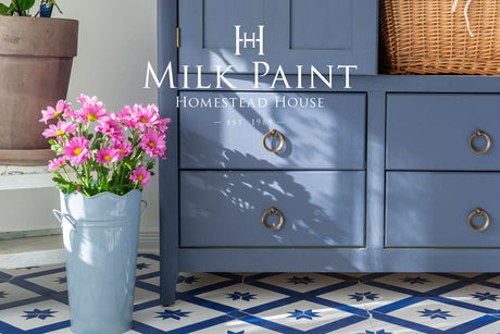 Blue cabinet in Homestead House Kurbits Indigo Milk Paint with brass handles, pink daisies, and blue patterned tiles.