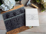 The Lace Stamp by IOD on a white book cover, with flowers and a small hammer nearby.