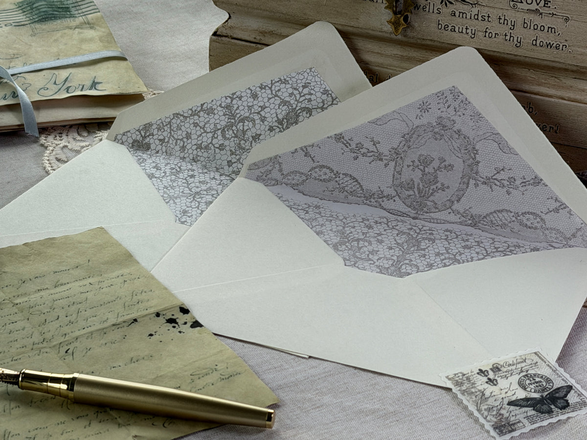 Lace Stamp by IOD with two floral-lined envelopes and handwritten letters on a wood surface.