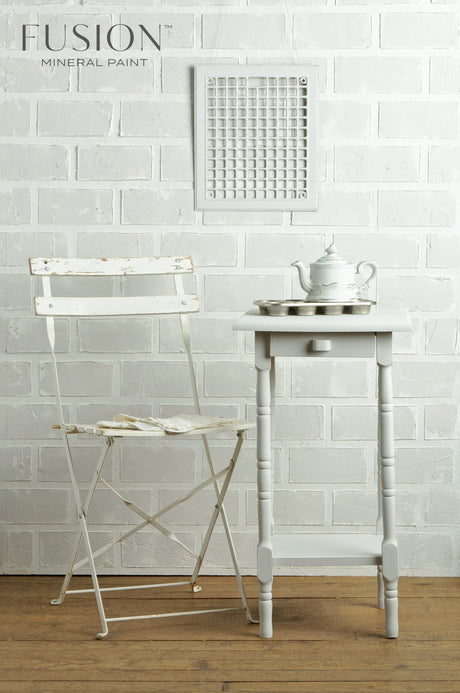 White chair, table, and teapot displayed beside a Fusion Mineral Paint Lamp White acrylic paint sign.