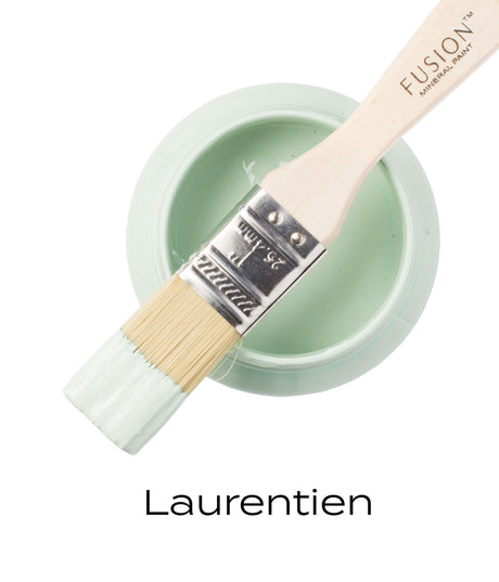 Paintbrush with light green Laurentien Fusion Mineral Paint rests across open Fusion Mineral Paint jar.