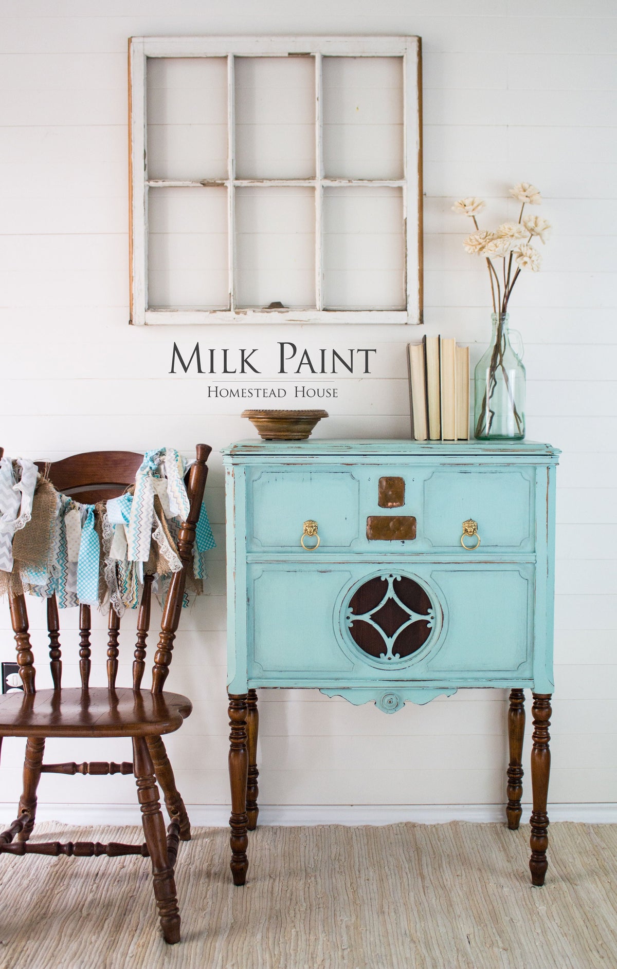 Vintage blue cabinet painted with Homestead House Laurentien Milk Paint, shown beside a chair, books, and glass vase.