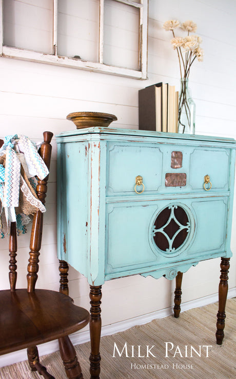 Blue vintage cabinet painted with Laurentien Milk Paint by Homestead House, next to a wooden chair.